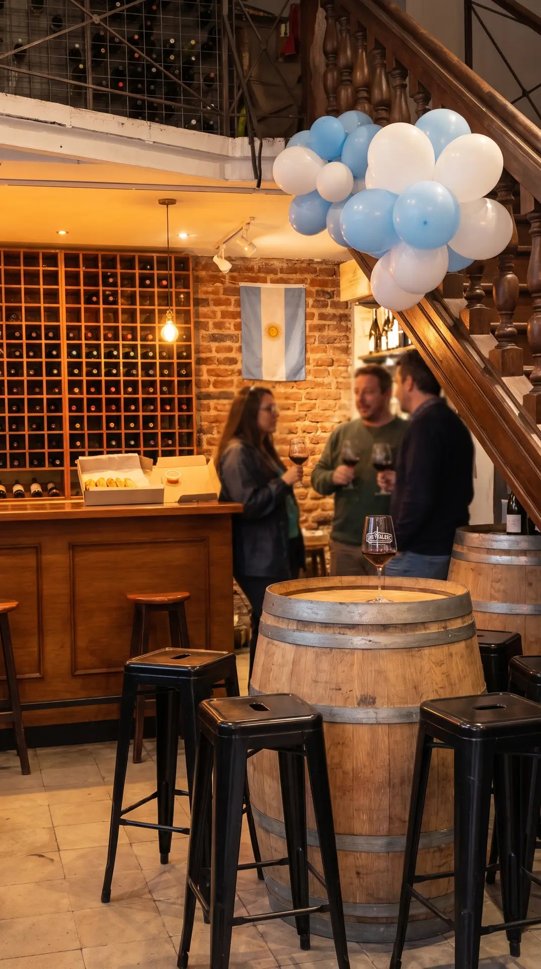 Adentro de Che Malbec: pared de botellas, mesa barril y banderitas argentinas